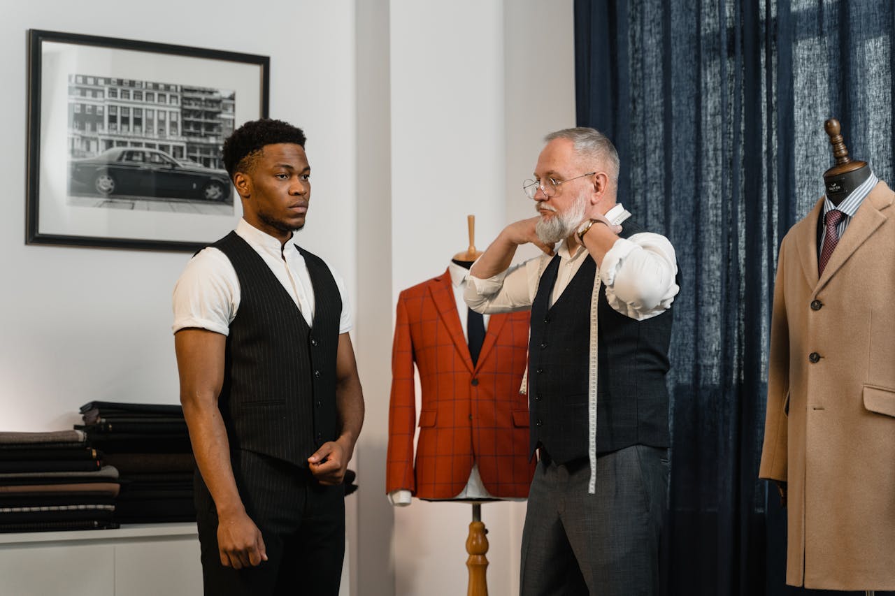 about-us A tailor measures a client in a stylish clothing atelier, showcasing luxury fashion.